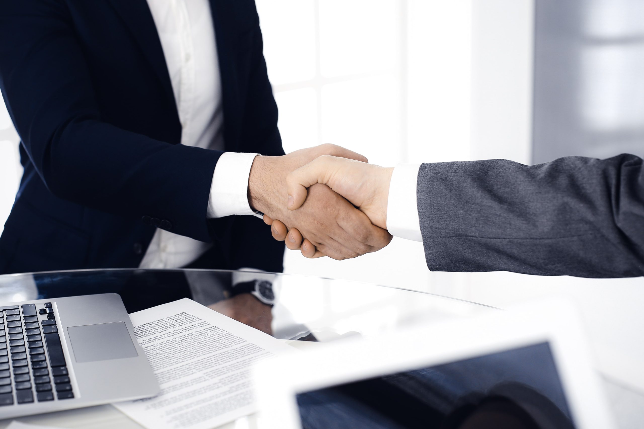 Unknown diverse business people are shaking hands finishing up meeting at the desk in office, close-up